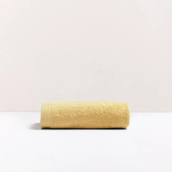 Luxe oker Florence handdoek van 100% GOTS-katoen, 600 g/m², hoge kwaliteit, zacht en absorberend.